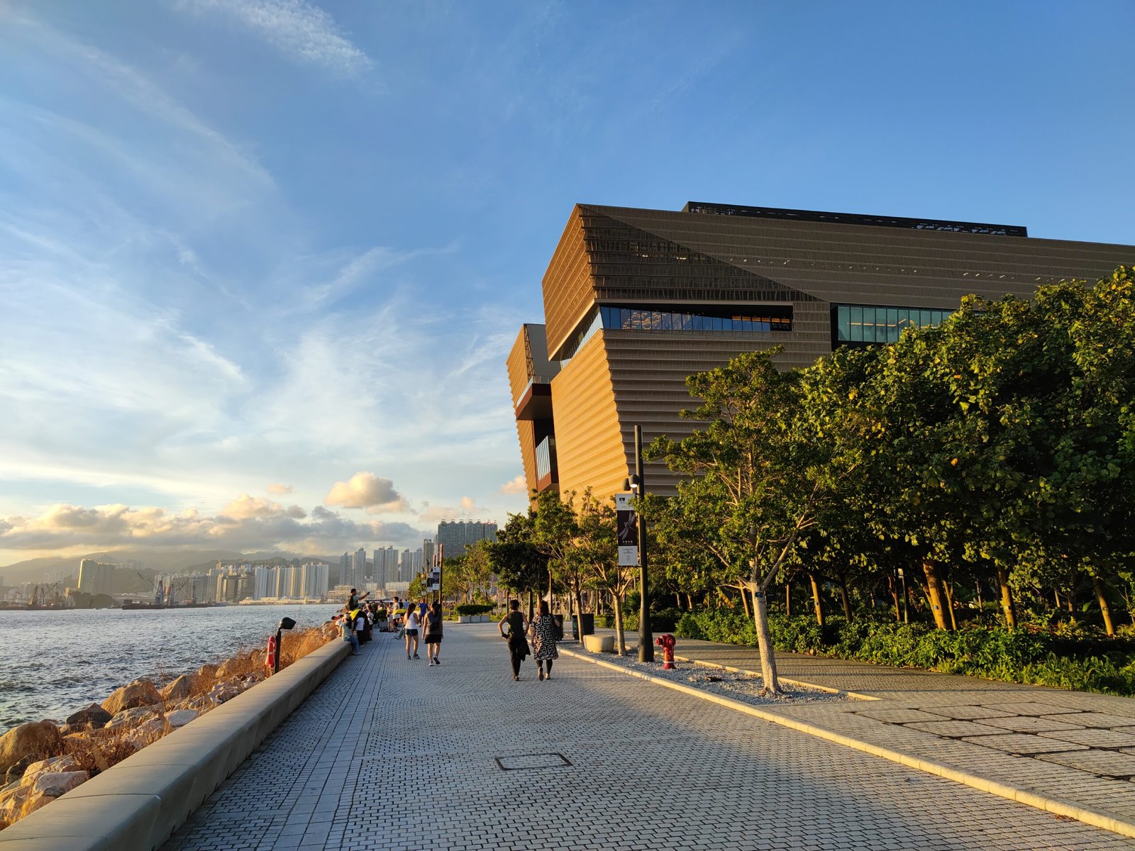 a group of people walking down a sidewalk next to a body of water